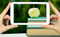 image of a cellphone taking a picture of an apple and a stack of books